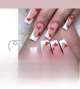 Detail view of long coffin press-on nails with white French tips and red heart patterns
