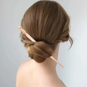 Detaillierte Ansicht einer rosa Haarspange aus Acetat in einem Dutt für Damenfrisuren