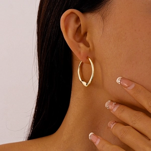 Close-up of model wearing gold irregular twisted geometric hoop earrings in a minimalist style