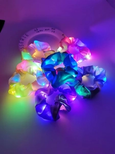 Close-up of vibrant LED glowing scrunchies on a white plate in low light setting
