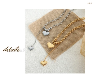 Detailed macro shot of 18K gold and silver double heart pendants on layered chunky chains