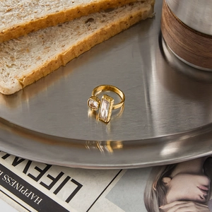 Minimalist gold open ring with dual rectangular crystals on a brushed metal tray