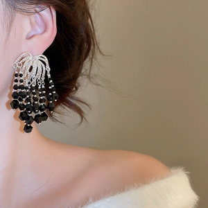 Close-up of dangling black crystal tassel earrings with sparkling rhinestones on model
