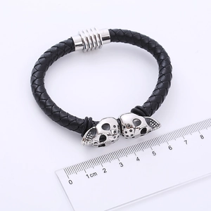 Nahaufnahme von schwarzem geflochtenem Lederarmband mit silbernen Totenköpfen und Magnetverschluss