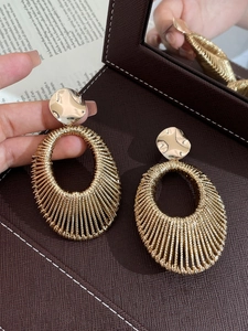 Detailed close-up of gold velvet weave hollow oval earrings with textured metallic finish