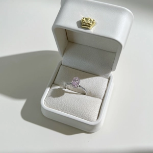 Macro shot of oval pink gemstone ring with diamond accents in a white jewelry gift box