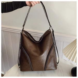 Detail showing high-quality dark brown soft leather texture and front zippers on the bag