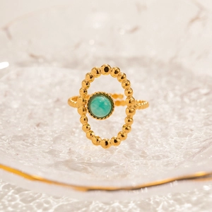 Macro shot of gold vintage ring with oval turquoise stone on artistic glass base
