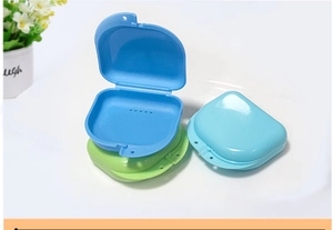 Detail of colorful dental retainer cases with drainage holes in blue and green plastic