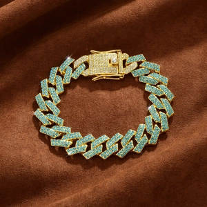 Detailed macro view of 15mm gold Cuban link chain with light blue rhinestones on velvet