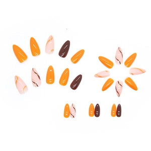 Glossy orange and chocolate almond press-on nails with golden glitter wave patterns
