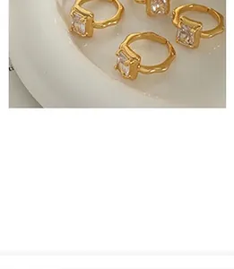 Detail of gold-plated adjustable rings with square zircons on a white ceramic plate
