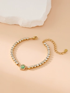 Detail of gold bracelet with green hexagonal gemstone and pavé rhinestones