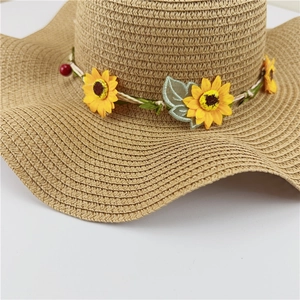 Detailed macro view of woven straw sun hat with yellow sunflower and green leaf crown