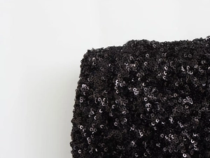 Macro detail of high-density black sequins on a sleeveless mini dress fabric