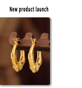 Détail de boucles d'oreilles dorées en forme de U suspendues sur un support en bois