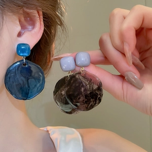 Close-up of oversized irregular resin earrings with marble pattern on a model