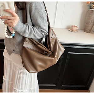 Grand sac cabas en cuir souple marron porté par un mannequin dans un décor minimaliste