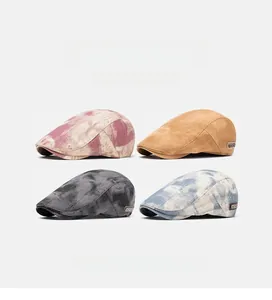 Detailed view of four vintage tie-dye and solid camel british style flat caps in cotton