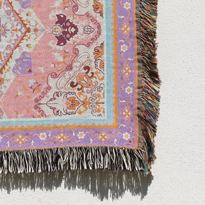Close-up of Bohemian woven blanket with pink floral patterns and colorful fringes