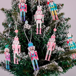 Detail of macaron-colored wooden nutcracker ornaments hanging on a snowy Christmas tree