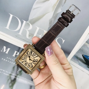 Detalle de reloj cuadrado dorado de lujo con bisel de diamantes y correa de cuero
