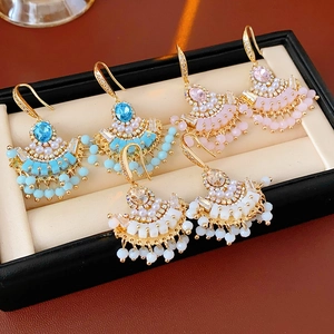 Vue détaillée de trois paires de boucles d'oreilles éventail avec pompons en cristal