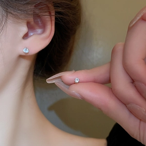 Close-up of minimalist six-prong silver stud earrings with sparkling round zircon stones