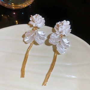 Detail of floral petal tassel earrings with white resin flowers and gold chain fringe