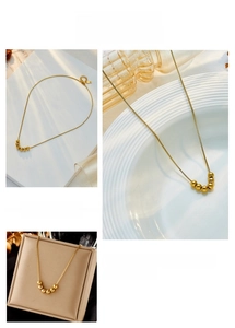 Detail showing five polished golden beads on a minimalist titanium steel chain necklace