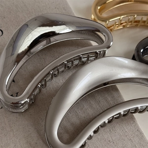Close-up of minimalist metal crescent hair claws in gold, silver, and matte black finish