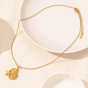 Macro detail of a gold stainless steel necklace with starfish and seashell pendants