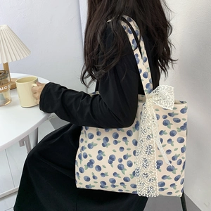 Detailed close-up of a floral canvas tote bag with a large white lace bow and blueberry print