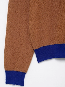 Detail von karamellbraunem Strickstoff mit dunkelblauen Rippbündchen und Kornstruktur