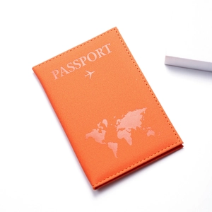 Close-up of orange faux leather passport holder with map silhouette and airplane icon