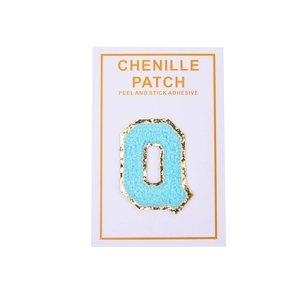 Detail of light blue chenille letter Q patch with gold glitter edge and adhesive backing