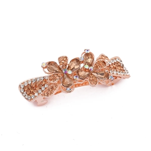 Detail of a golden metal hair clip with amber rhinestones in a double flower design