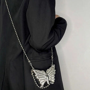 Elegant silver butterfly-shaped chain bag with rhinestones shown on a black suit jacket