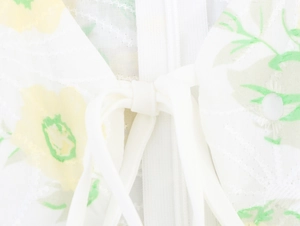 Detailed view of white floral dress with yellow flowers and front tie knot detail