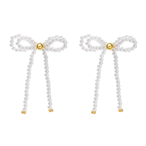 Detailed view of long bowknot earrings made of white pearls with golden center beads