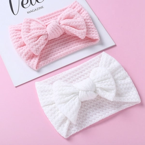 Detail view of pink and white knitted mesh baby headbands with large soft bow accents