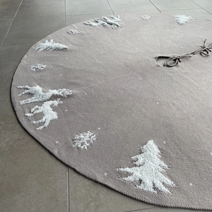 Detailed view of knitted Christmas tree skirt with reindeer patterns and ribbon ties