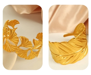Close-up of golden titanium steel bracelets with ginkgo leaf and feather hollow designs