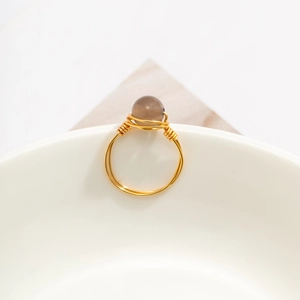 Detailed macro view of handmade gold wire wrapped ring with a grey stone bead