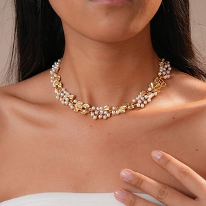 Close-up of vintage golden leaf and white pearl necklace on a model's neck