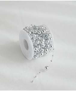Macro detail of silver electroplated plastic bead chain on a white spool for DIY decor