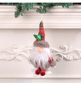 Close-up of plush Christmas gnome with wooden snowflake base hanging on pine branch