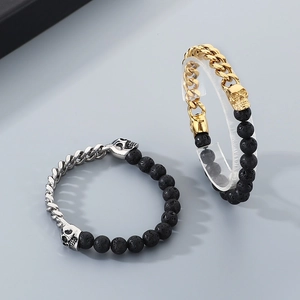 Detail of punk skull bracelet set with gold chain and black volcanic stone beads