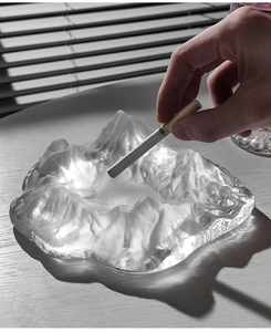 Close-up of glacier-shaped glass ashtray with iceberg texture on a wooden desk