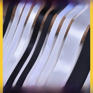 Close-up of black and white grosgrain and satin ribbons neatly wound on paper tubes